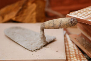 A trowel is actively shaping mortar on a brick, illustrating the technique of constructing with bricks.